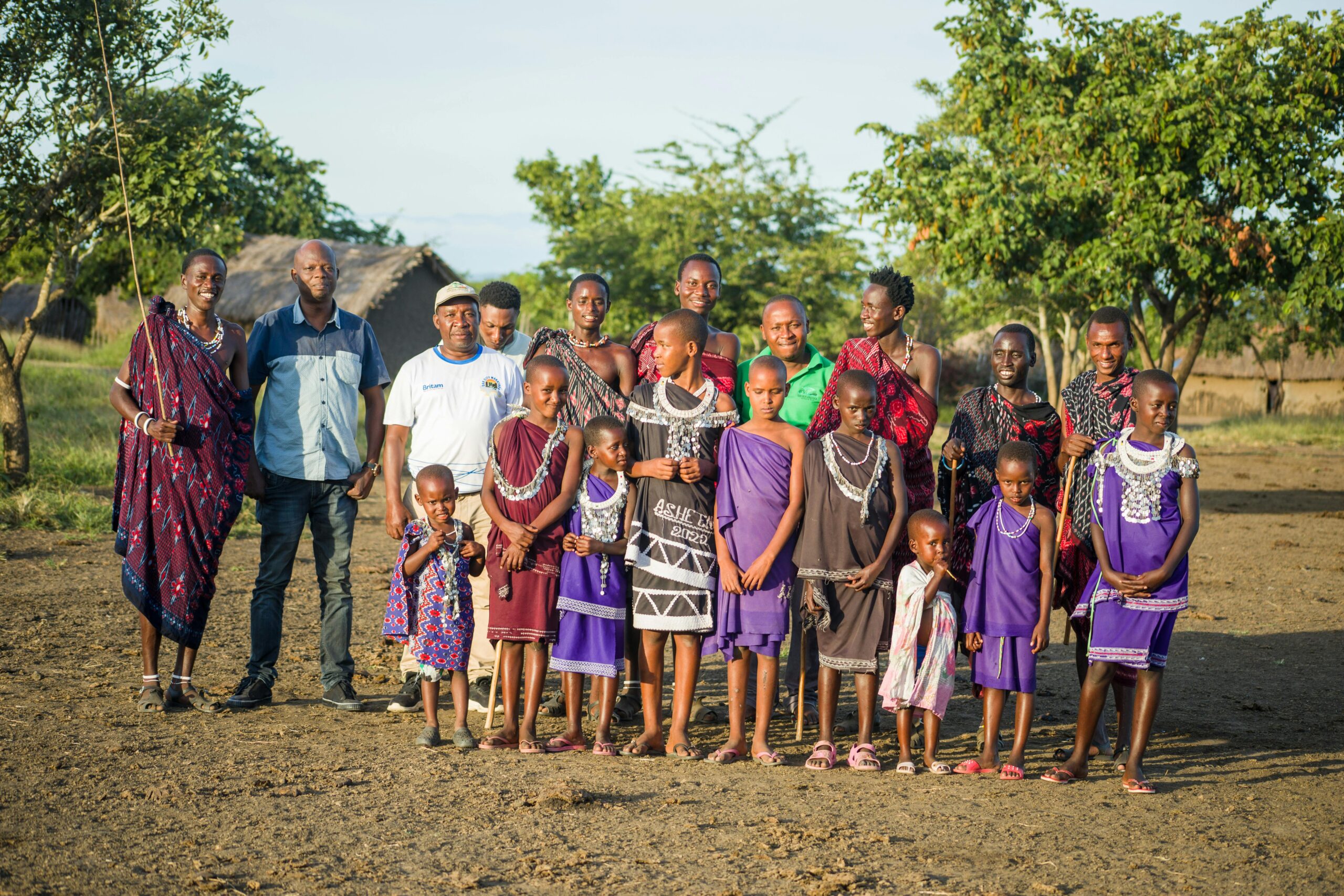 A diverse group of Tanzanian people in traditional attire outdoors, showcasing cultural heritage.