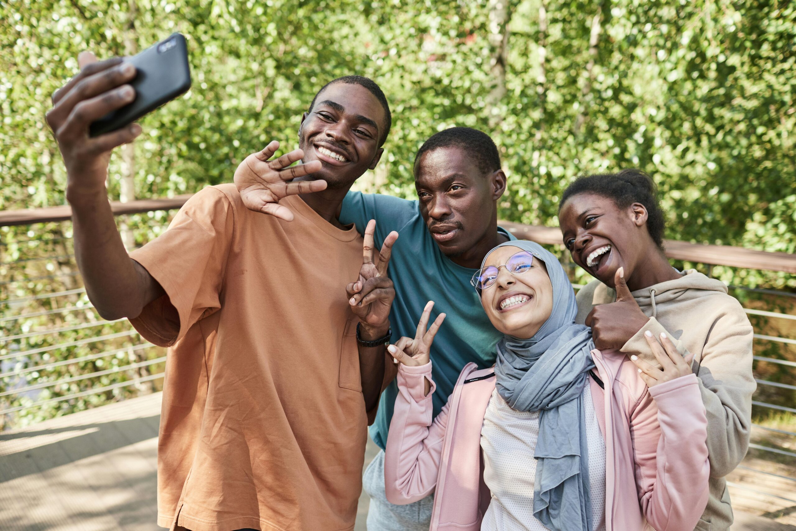 Diverse group of friends enjoying a selfie in a sunny park, showcasing joy and friendship.